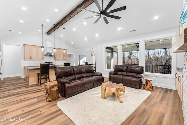 living room featuring a wealth of natural light, lofted ceiling with beams, and light wood-type flooring