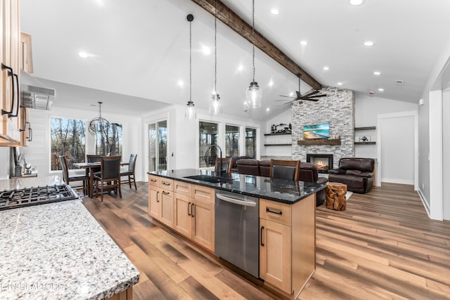 kitchen with pendant lighting, stainless steel appliances, dark stone countertops, sink, and a large island