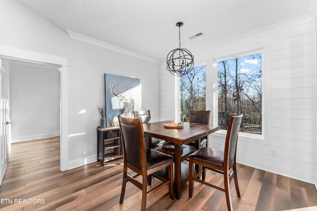 dining space featuring dark hardwood / wood-style flooring, crown molding, and a notable chandelier