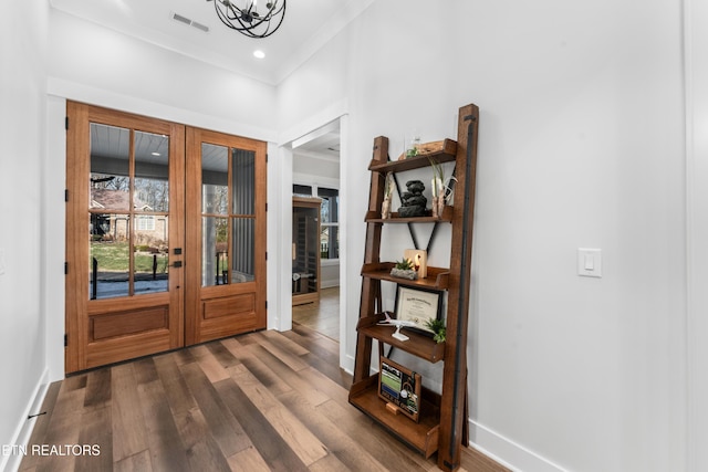 entrance foyer featuring french doors, dark hardwood / wood-style floors, ornamental molding, and a chandelier