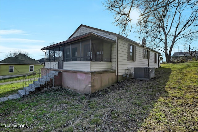 view of side of home with a yard, cooling unit, and a sunroom