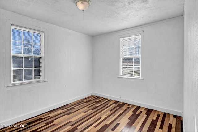 unfurnished room with a textured ceiling and hardwood / wood-style floors