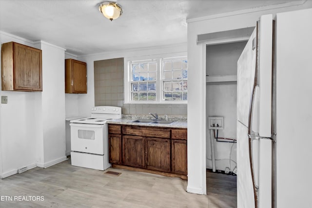 kitchen with sink, white appliances, ornamental molding, and light hardwood / wood-style floors