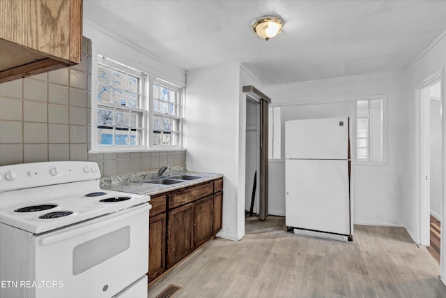 kitchen featuring white appliances, light hardwood / wood-style flooring, backsplash, ornamental molding, and sink