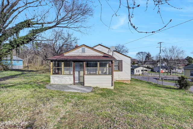 bungalow-style house featuring a front yard, a patio, and a sunroom