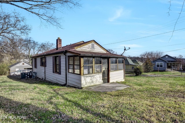 rear view of house with a lawn and a sunroom