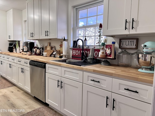 kitchen with sink, stainless steel dishwasher, butcher block counters, and white cabinetry