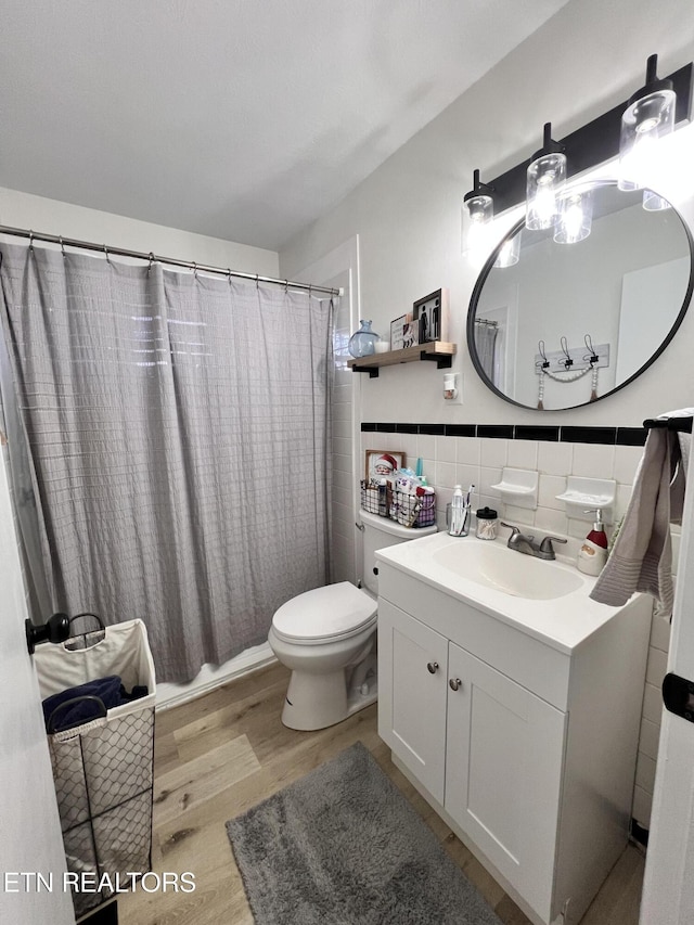 bathroom with toilet, hardwood / wood-style floors, tile walls, backsplash, and vanity