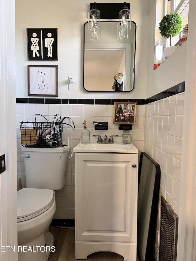 bathroom featuring toilet, vanity, tile walls, and hardwood / wood-style flooring