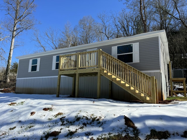 snow covered back of property featuring a wooden deck