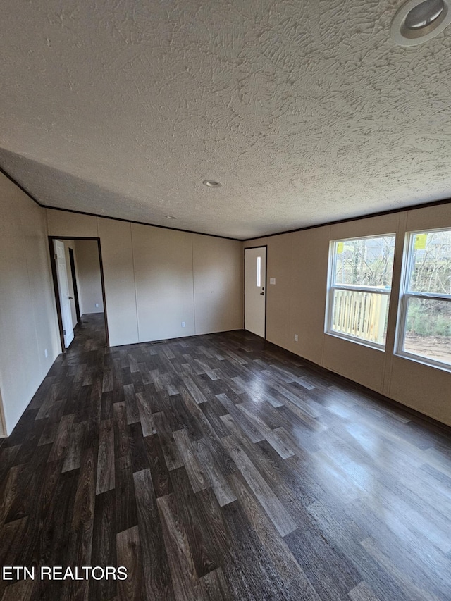 spare room featuring dark wood-type flooring and a textured ceiling