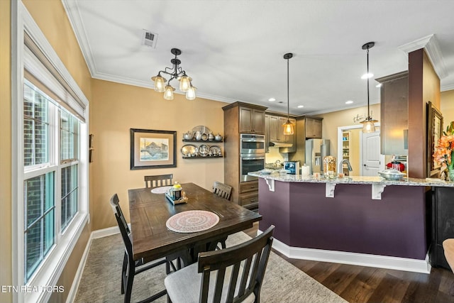 dining area featuring dark hardwood / wood-style floors, crown molding, and a notable chandelier