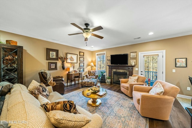 living room with dark wood-type flooring, crown molding, and ceiling fan