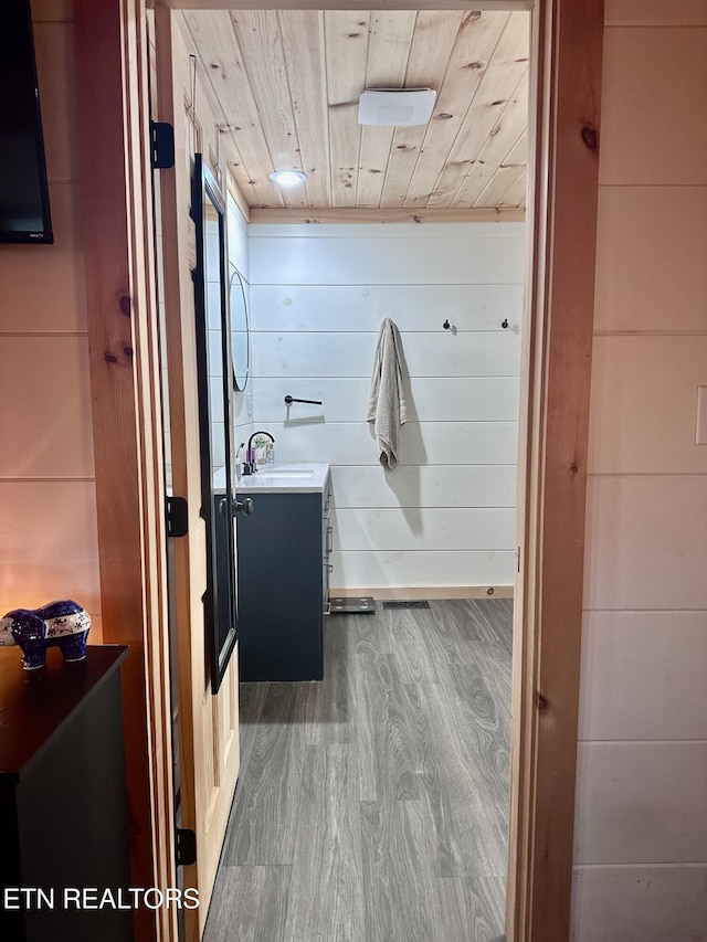 bathroom featuring wood walls, wood ceiling, wood-type flooring, and vanity