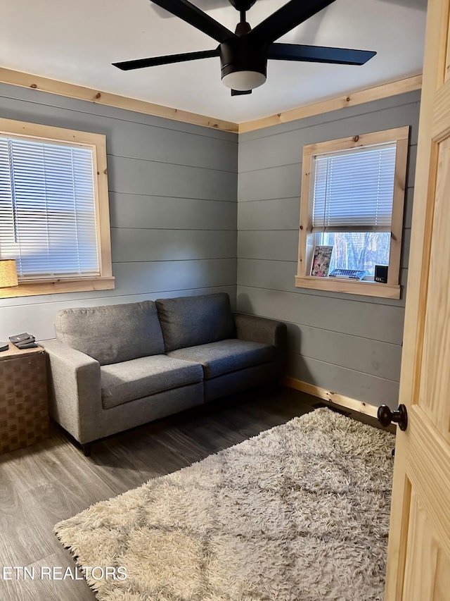 living room with ceiling fan, hardwood / wood-style floors, and wood walls