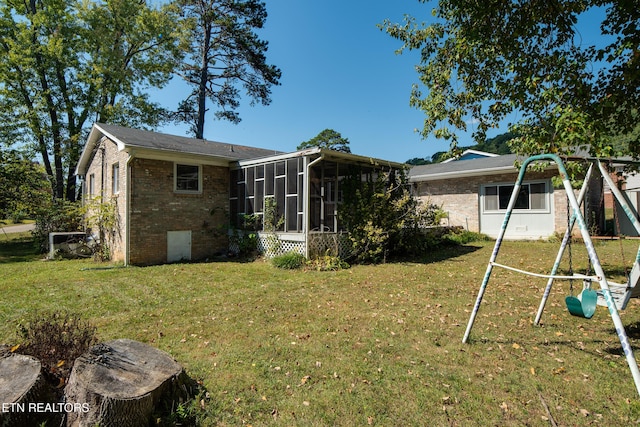 back of property featuring a lawn, a playground, and a sunroom