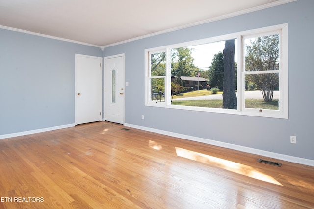 empty room featuring a healthy amount of sunlight, crown molding, and light hardwood / wood-style flooring