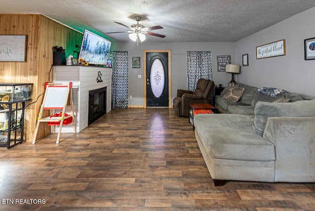 living room featuring ceiling fan, a textured ceiling, dark hardwood / wood-style flooring, and wood walls