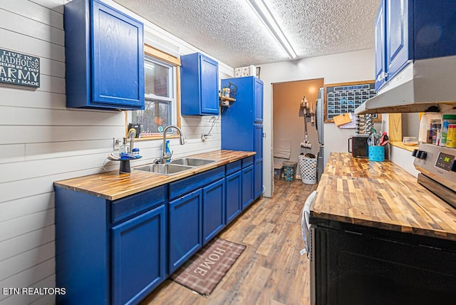 kitchen with wooden counters, sink, wooden walls, hardwood / wood-style flooring, and blue cabinets