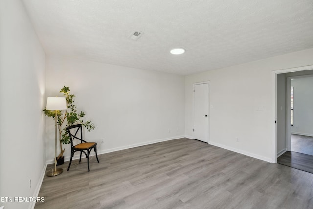 empty room with light hardwood / wood-style flooring and a textured ceiling