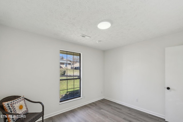 unfurnished room featuring hardwood / wood-style floors and a textured ceiling