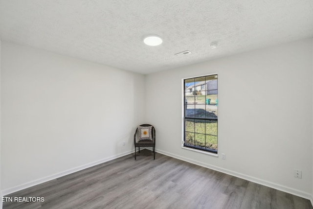 spare room with wood-type flooring, a wealth of natural light, and a textured ceiling