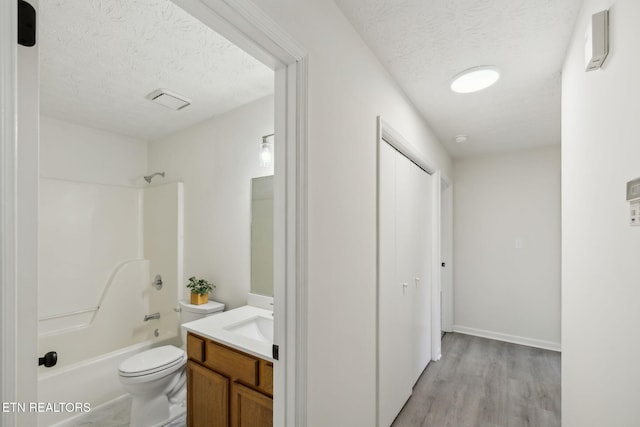 full bathroom featuring shower / tub combination, wood-type flooring, vanity, toilet, and a textured ceiling