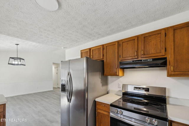 kitchen featuring stainless steel appliances, decorative light fixtures, a textured ceiling, and light wood-type flooring