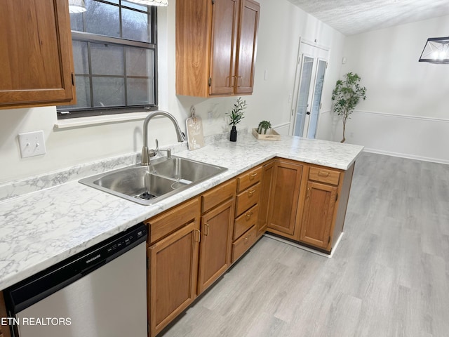 kitchen with light hardwood / wood-style floors, stainless steel dishwasher, kitchen peninsula, and sink