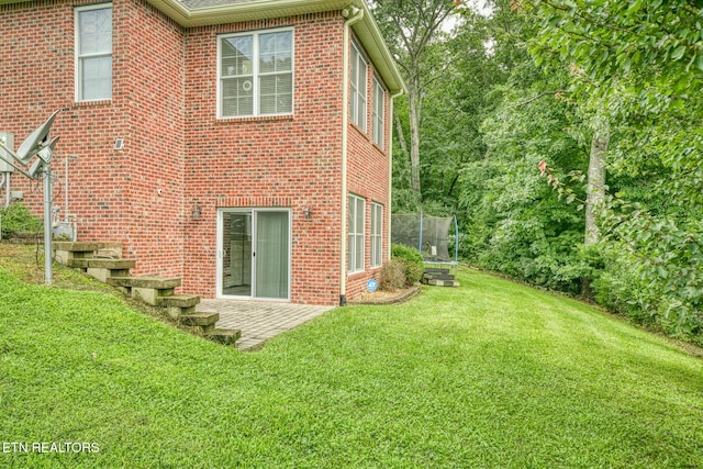 rear view of house featuring a lawn, a trampoline, and a patio