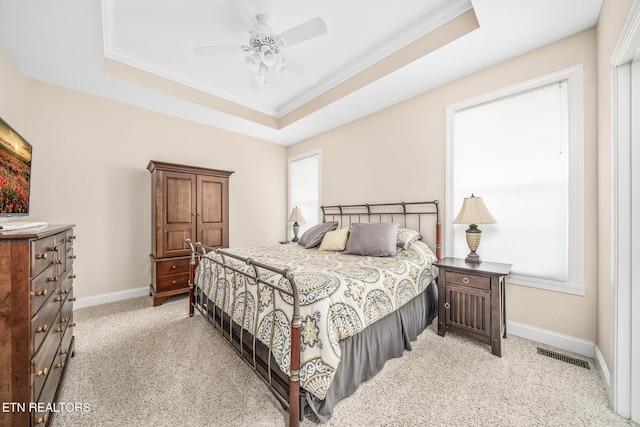 bedroom with ceiling fan, light carpet, a tray ceiling, and ornamental molding