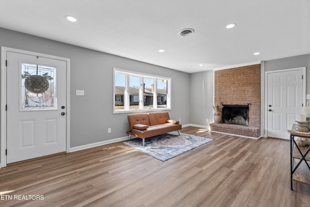 foyer featuring a brick fireplace, a healthy amount of sunlight, and hardwood / wood-style floors