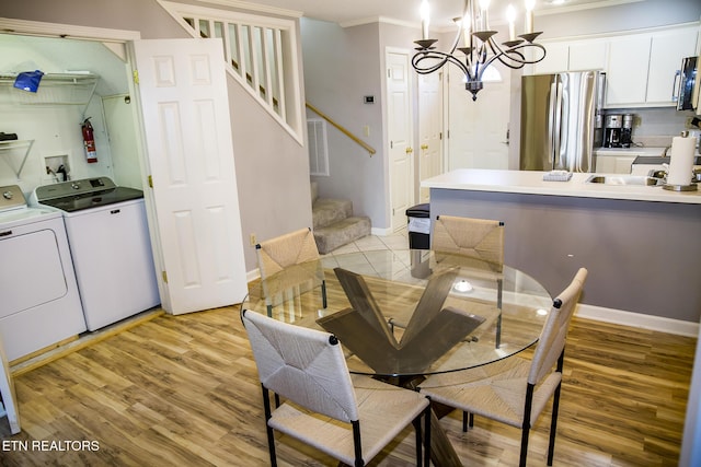 dining room featuring light hardwood / wood-style floors, ornamental molding, washing machine and dryer, a chandelier, and sink