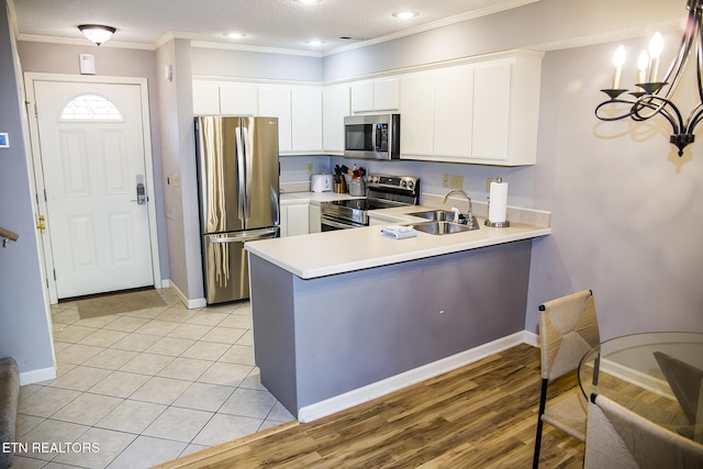 kitchen featuring kitchen peninsula, stainless steel appliances, white cabinets, and sink