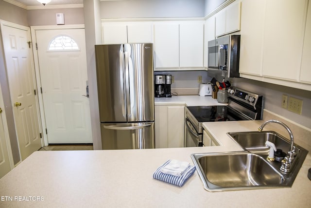 kitchen featuring white cabinets, crown molding, appliances with stainless steel finishes, and sink