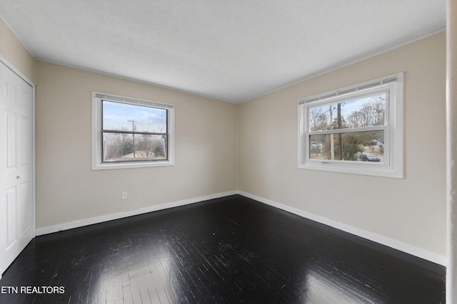 spare room featuring dark wood-type flooring and a textured ceiling