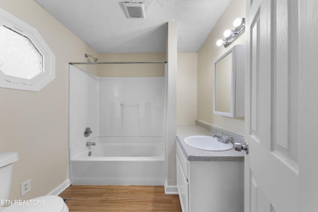 full bathroom with a textured ceiling, vanity, shower / bath combination, toilet, and hardwood / wood-style flooring