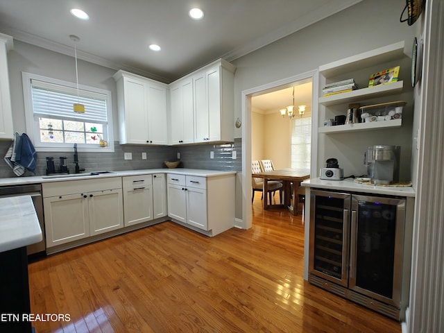 kitchen featuring sink, decorative light fixtures, beverage cooler, and white cabinets