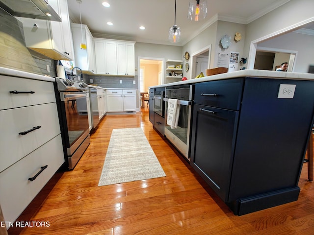 kitchen featuring white cabinetry, decorative light fixtures, ornamental molding, and stainless steel appliances