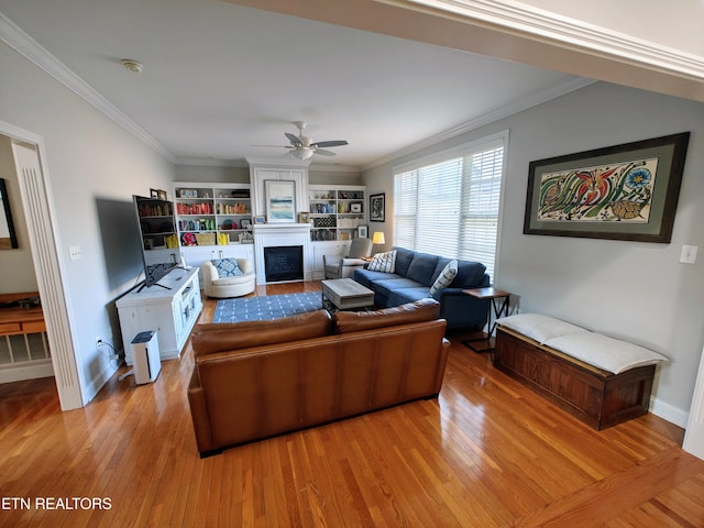 living room featuring hardwood / wood-style flooring, ornamental molding, and a large fireplace