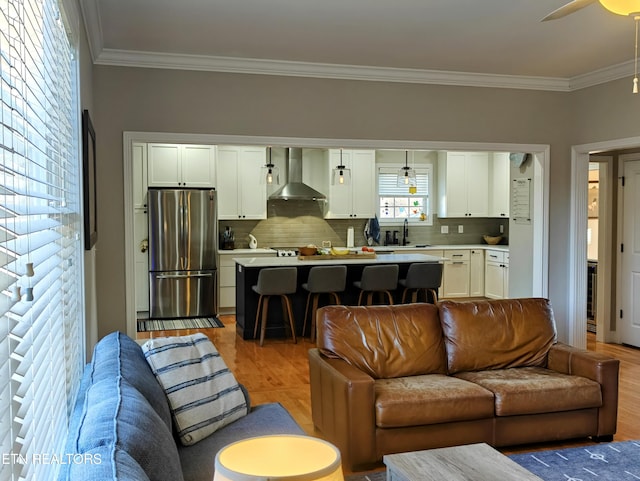 living room with crown molding, sink, ceiling fan, and light wood-type flooring