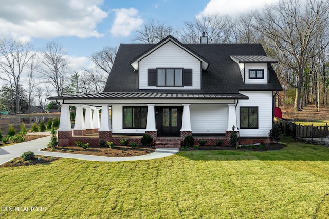 modern farmhouse with covered porch, a shingled roof, and a front lawn