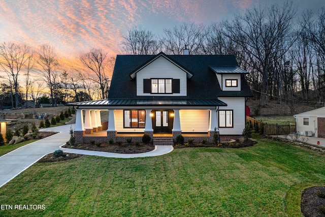 view of front of home with a standing seam roof, a porch, and a yard