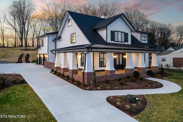 view of front of home with a porch, a garage, and a lawn