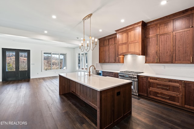 kitchen featuring pendant lighting, sink, a kitchen island with sink, high end stainless steel range, and dark wood-type flooring