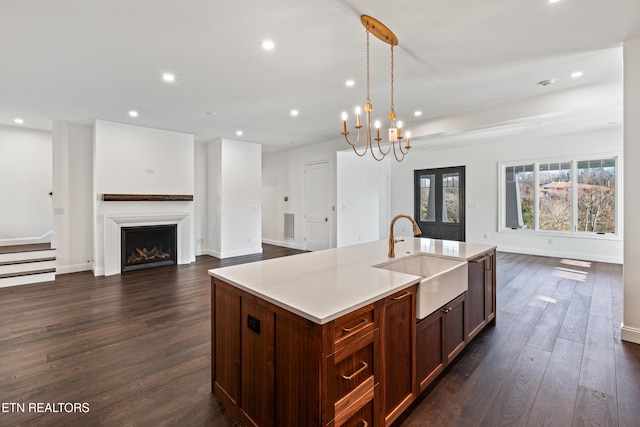 kitchen featuring pendant lighting, an island with sink, sink, dark hardwood / wood-style flooring, and french doors