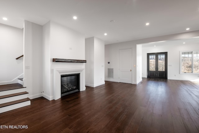 unfurnished living room with dark hardwood / wood-style floors and french doors