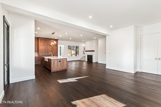 unfurnished living room featuring sink, a notable chandelier, and dark wood-type flooring