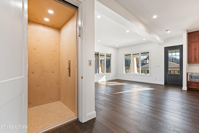 interior space featuring elevator, dark hardwood / wood-style floors, and beam ceiling