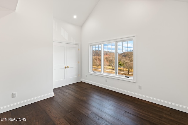 empty room with dark wood-type flooring and high vaulted ceiling